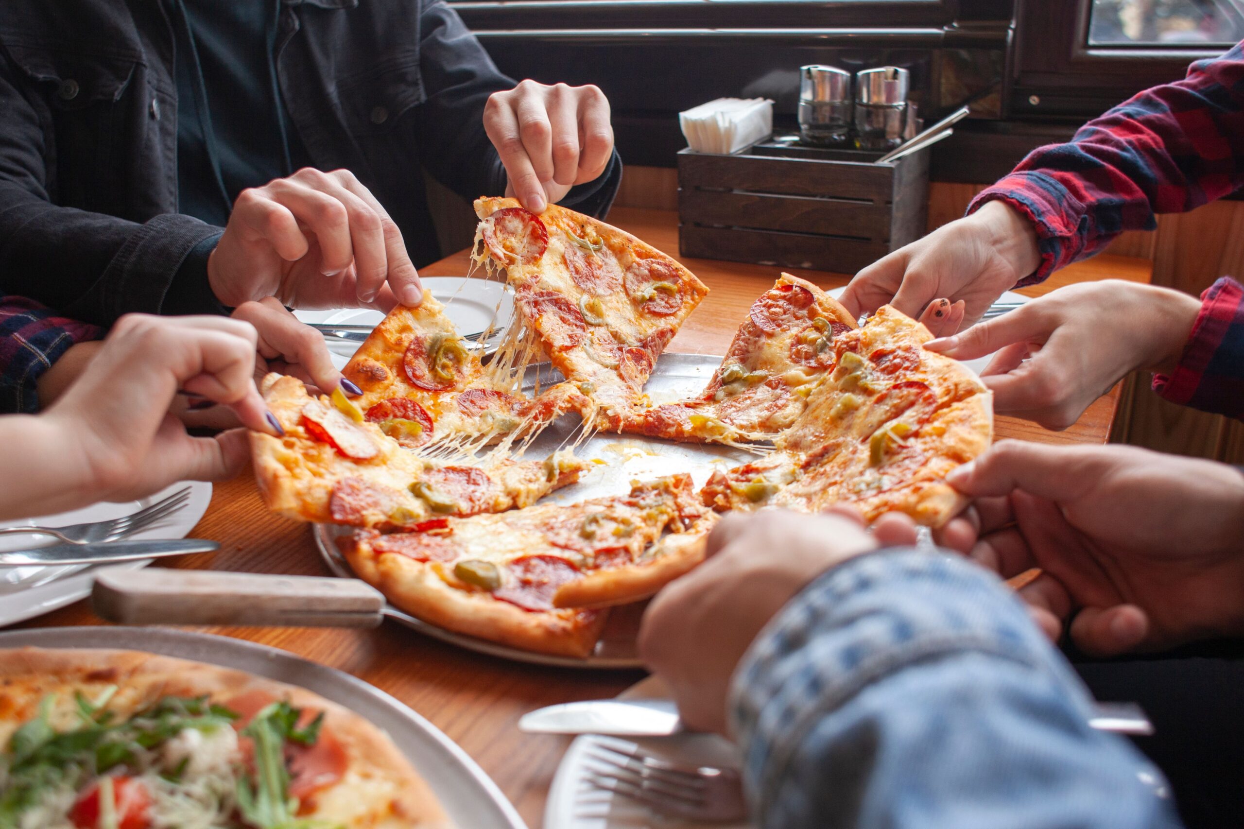 group sharing pizza at restaurant scaled