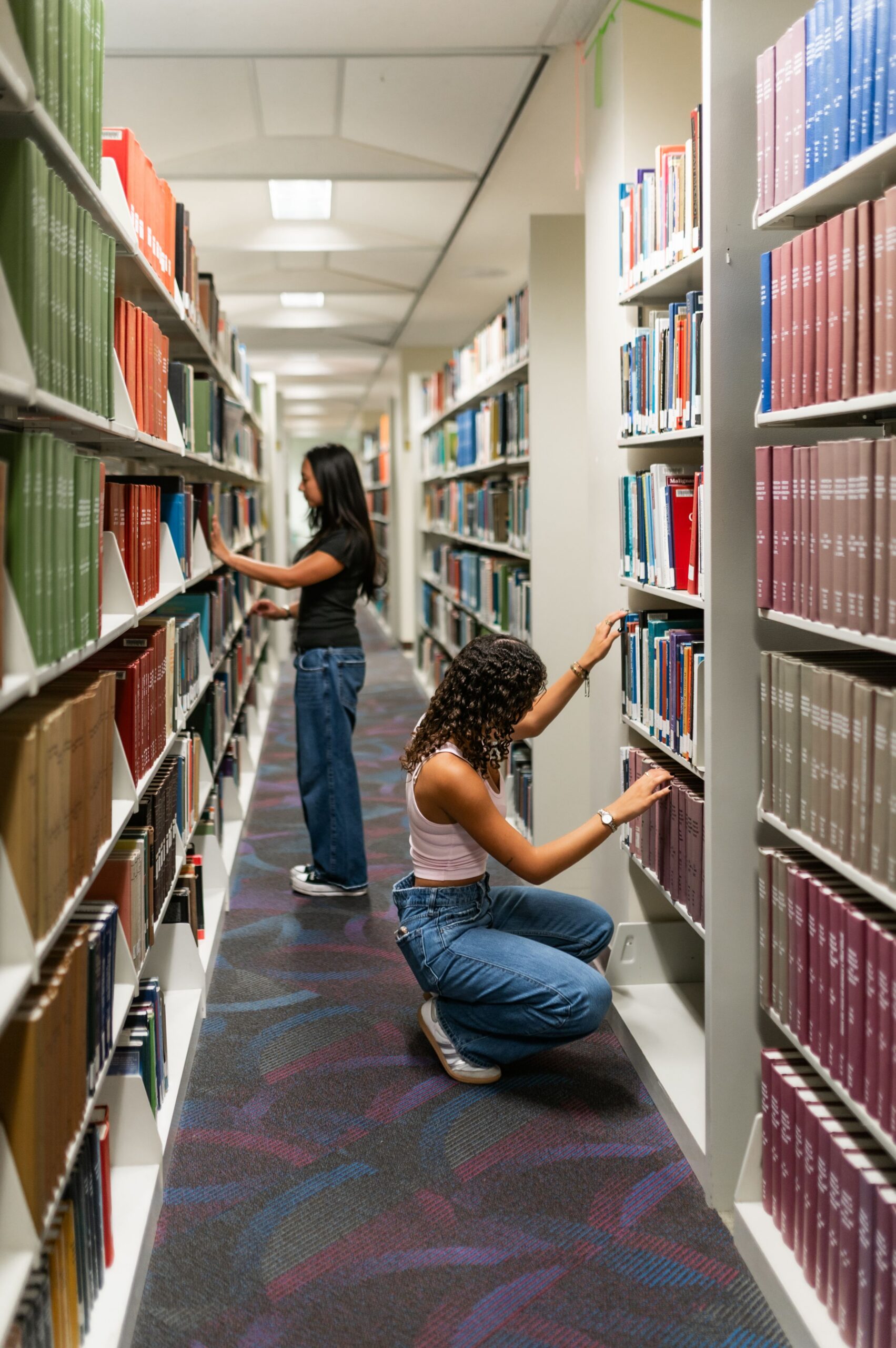 students searching university library shelves scaled
