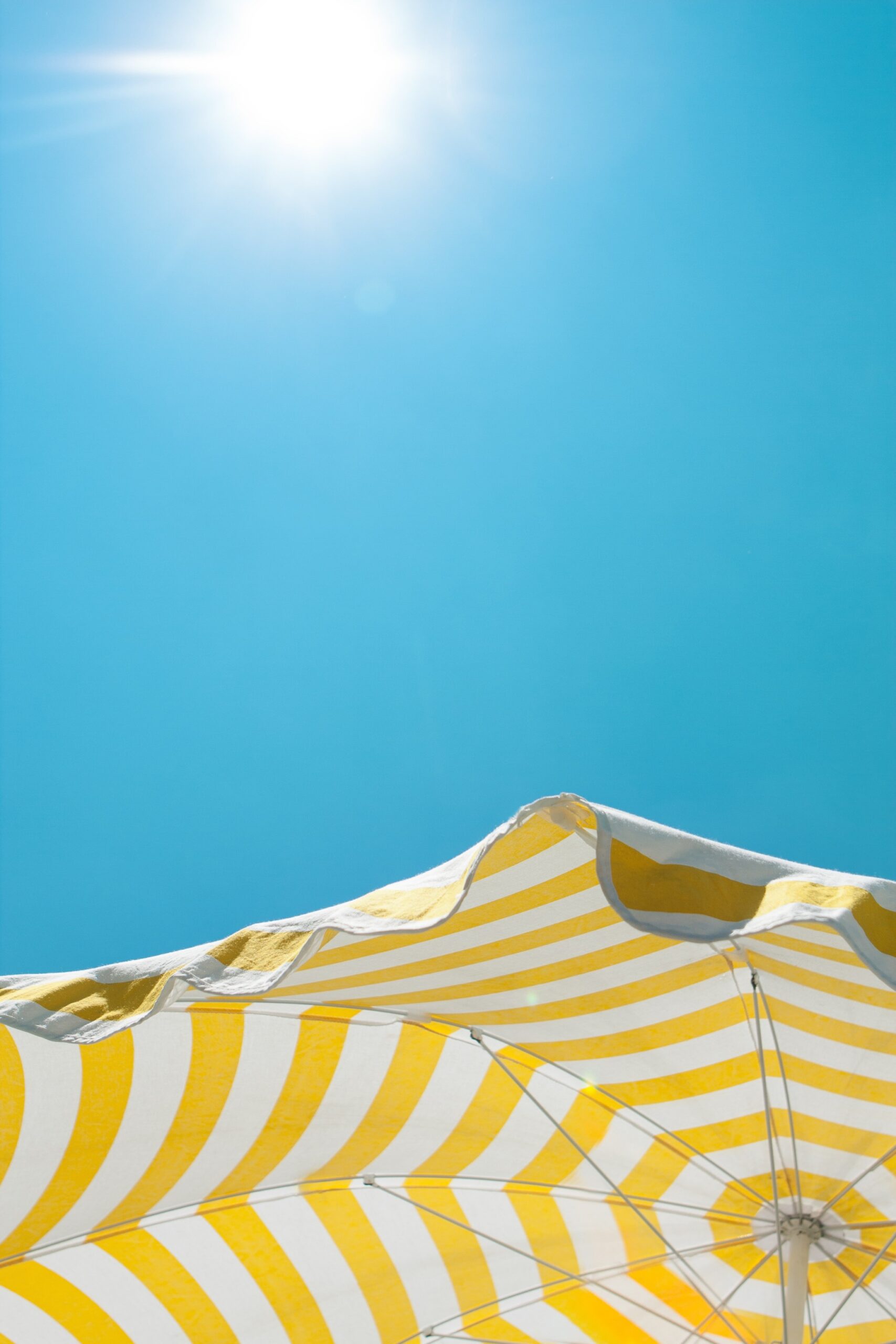 Bright sun and striped umbrella scaled